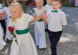 dziewczynka w białej sukience z różą w ręce, chłopiec w białej koszuli