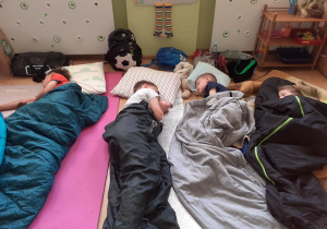 czterej chłopcy śpią w śpiworach w klasie