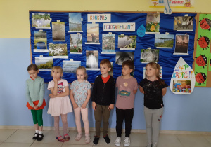 grupa dzieci - uczestników konkursu pozuje do zdjęcia , w tle prace konkursowe