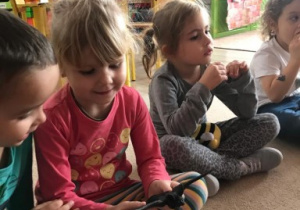 dzieci siedzą na dywanie i przekazują sobie gumowego nietoperza