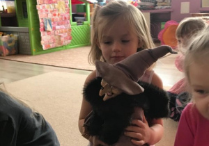 dziewczynka trzyma w rękach czarownicę zabawkę