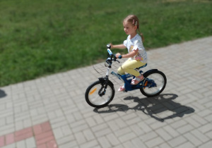 dziewczynka jeździ na rowerze w ogrodzie przedszkolnym