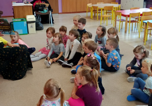 dzieci siedzą na dywanie i słuchają czytanego przez nauczycielkę opowiadania
