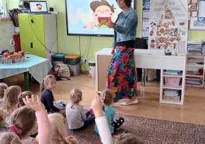 dzieci siedzą na dywanie słuchają prelekcji pani dietetyczki, na tablicy multimedialnej prezentacja zdrowych nawyków