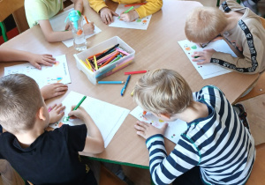 grupa dzieci przy stoliku, kolorują