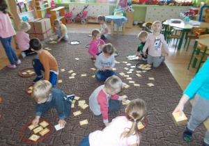 dzieci w grupach bawia się na dywanie planszami z literami