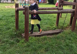 Dziewczynka korzysta z huśtawki w ogrodzie przedszkolnym.