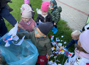 Dzieci zbierają śmieci i wrzucają je do niebieskiego worka.