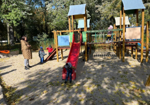 Dzieci bawią się na placu zabaw. Podczas zabawy korzystają ze sprzętu terenowego.