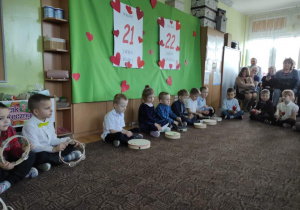 dzieci siedzą na dywanie i grają na instrumentach