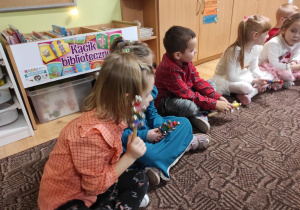 grupa dzieci siedzi na dywanie , obok leżą instrumenty