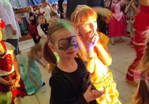 Dzieci uczestniczą w zabawie naśladowczej podczas przedszkolnego balu. Mają na sobie stroje karnawałowe.