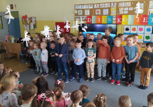 Chłopcy stoją przed dziewczynkami i Paniami- śpiewają piosenkę z okazji Dnia Kobiet.