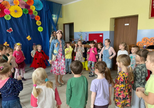 Nauczycielka przebrana za wiosnę tańczy z dziećmi do wiosennej piosenki.