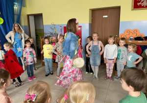 Nauczycielka przebrana za wiosnę śpiewa i tańczy z dziećmi do wiosennej piosenki.