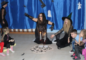 czarownice Abra i Kadabra, obok siedzą dzieci