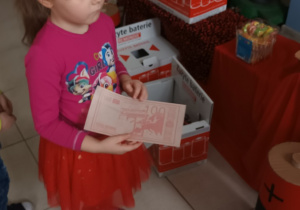 dziewczynka trzyma w ręce spożywcze "euro", które otrzymała za przyniesione zużyte baterie