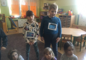 dwoje dzieci z obrazkami urządzeń, które wykorzystują internet. prezentują je pozostałym dzieciom