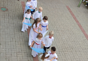 grupa dzieci tańczy walca , dziewczynki w białych sukienkach, chłopcy ubrani na galowo
