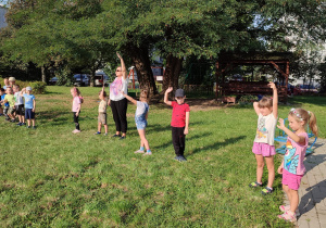 grupa dzieci w ogrodzie przedszkolnym bierze udział w zabawie ruchowej