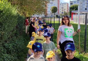 pracownicy przedszkola i dzieci maszerują ulicami miasta , dzieci w czapeczkach z logo przedszkola, z emblematami grup, z instrumentami w rękach. Niektóre z nich przebrane w stroje grupowe