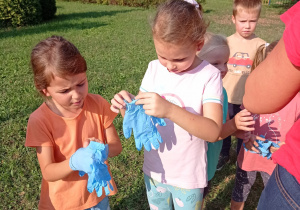 grupa dzieci zakłada gumowe rękawiczki i przygotowuje się do sprzątania