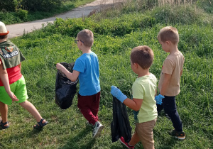 grupa dzieci z workami sprząta wyznaczony teren