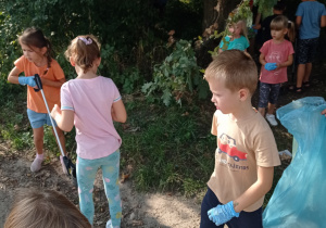 grupa dzieci z workami sprząta wyznaczony teren