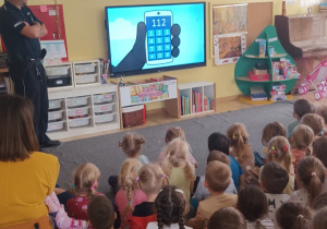 Dzieci oglądają prezentację multimedialną, dotyczącą numerów alarmowych