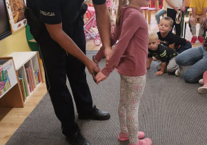 Policjant zakłada dziewczynce kajdanki