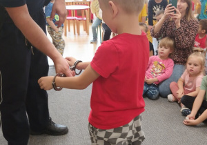 Policjant zakłada chłopcu kajdanki