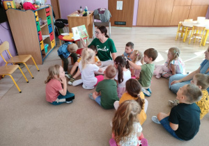 mama jednego z przedszkolaków czyta dzieciom, które siedzą wokół niej na dywanie