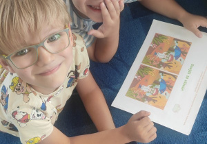 dwóch chłopców leży na dywanie, oglądają ilustracje