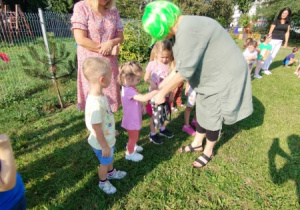 dzieci i nauczycielki zebrane w ogrodzie biorą udział w zabawach o tematyce eko