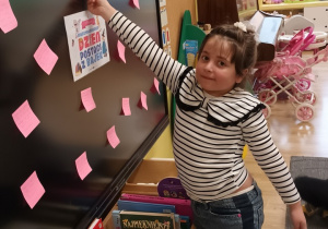 Dziewczynka wykonuje zadanie wskazane przez nauczycielkę. Wybiera jedną z karteczek, przyczepioną do tablicy.