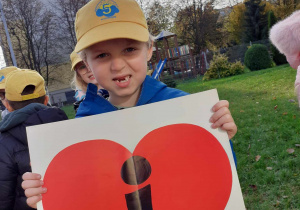 chłopiec na podwórku przedszkolnym, w dłoniach trzyma serce z literką I