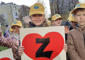 dziewczynka na podwórku przedszkolnym, w dłoniach trzyma serce z literką Z