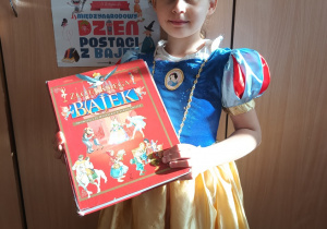 dziewczynka w przebraniu księżniczki pozuje do zdjęcia z książką w dłoni