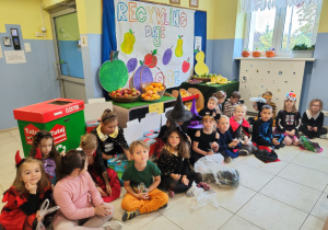 grupa dzieci pozuje do zdjęcia przy stoisku z owocami przygotowanym w przedszkolnej szatni