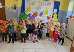 grupa dzieci w satni pozuje do wspólnego zdjęcia, w dłoniach trzymają owoce