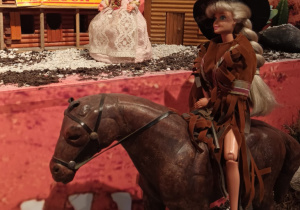 ekspozycja zabawek - lalka na koniu, w tle budynki z westernu