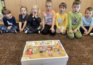 grupa dzieci siedzi na dywanie, przed nimi "naukowe pudełko"
