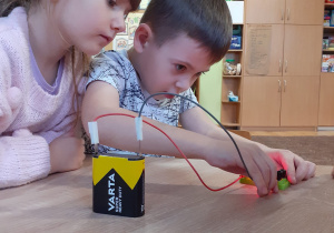 dwoje dzieci wykonuje eksperyment związany z prądem