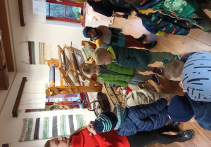 grupa dzieci w muzeum, słuchają pani przewodniczki opowiadającej o tkaczach zgierskich