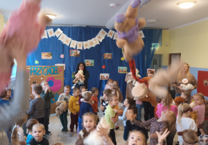 duża grupa dzieci tańczących w szatni, podrzucają misie w górę