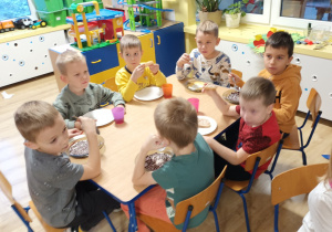 grupa dzieci przy stolikach w klasie, jedzą
