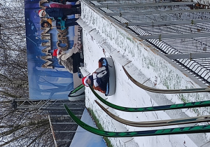 dziecko na "pontonie" zjeżdża po śniegu z górki