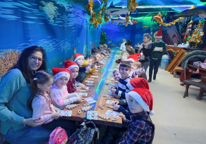 grupa dzieci i nauczycielka w pomieszczeniu w malinowym Grodzie, ściany stylizowane na podwodny świat,