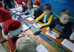 grupa dzieci w pomieszczeniu w malinowym Grodzie, ściany stylizowane na podwodny świat, dzieci wykonują zadanie na kartach pracy