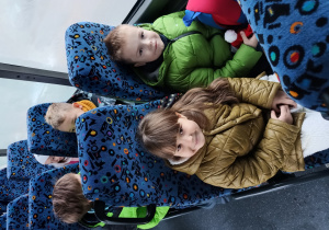 dzieci siedzą na fotelach w autobusie, jadą na wycieczkę